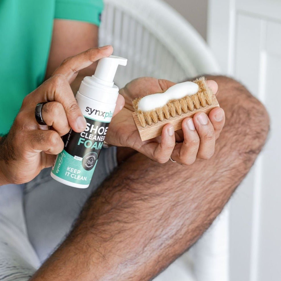 man spraying synxplus shoe cleaner foam onto brush, keep kicks clean, shoes, sneakers