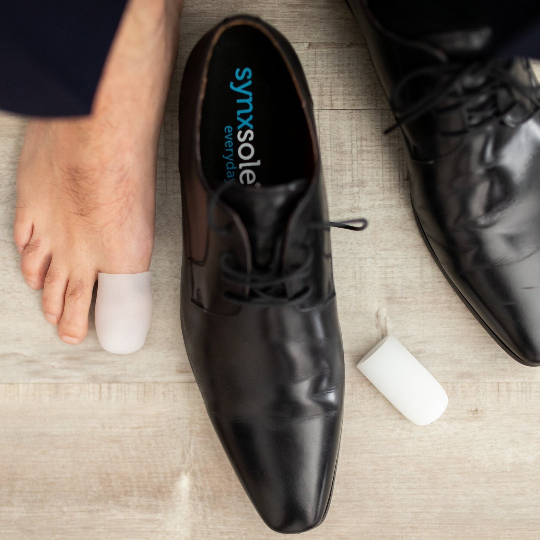 man with foot next to work shoe big toe wearing synxgeli large toe sleeve, ideal for treating, reducing or preventing corns, blisters and toe deformities
