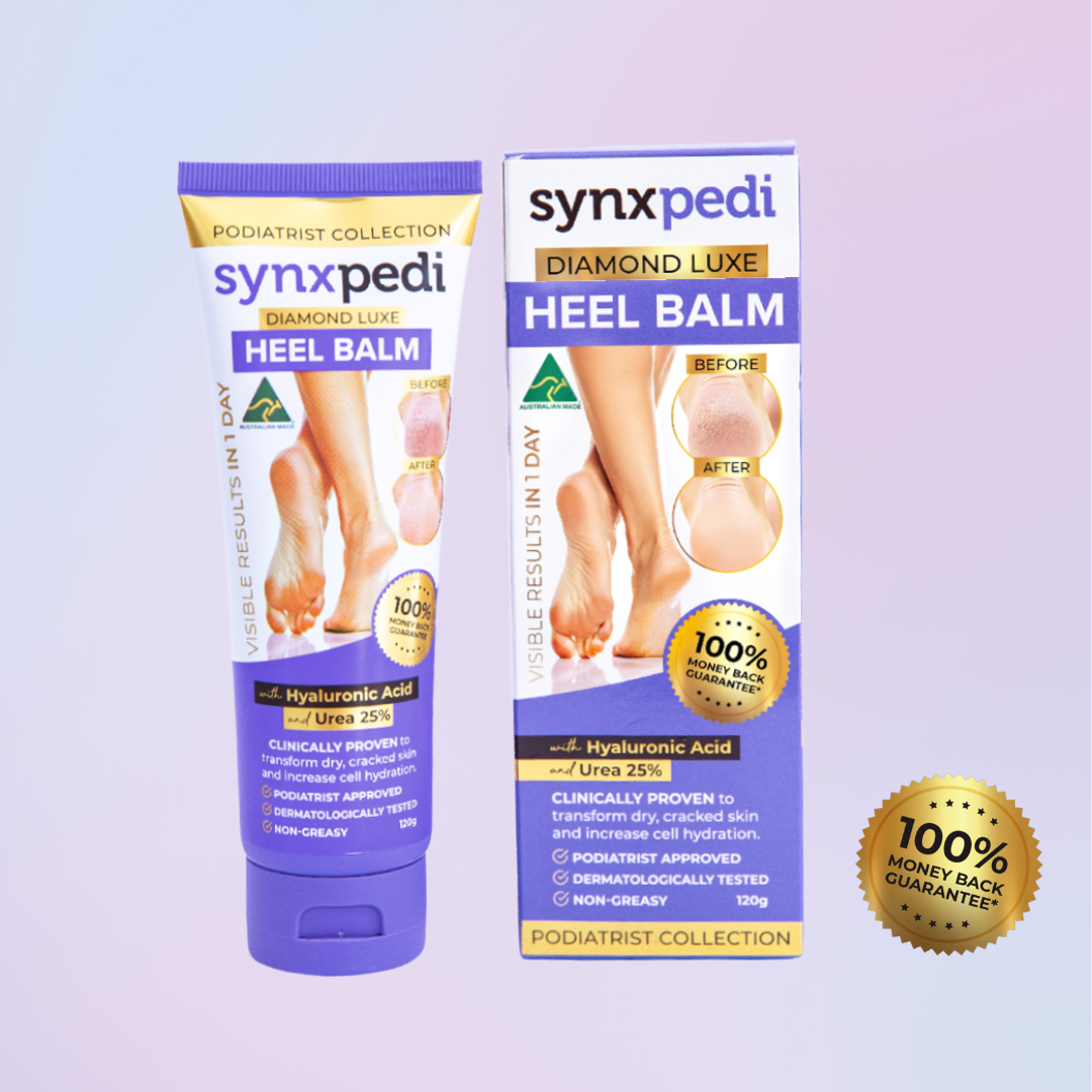 Synxpedi Diamond Luxe Heel Balm shown as a purple squeeze tube next to its matching retail box, with a gold '100% Money Back Guarantee' badge on a soft lavender gradient background.