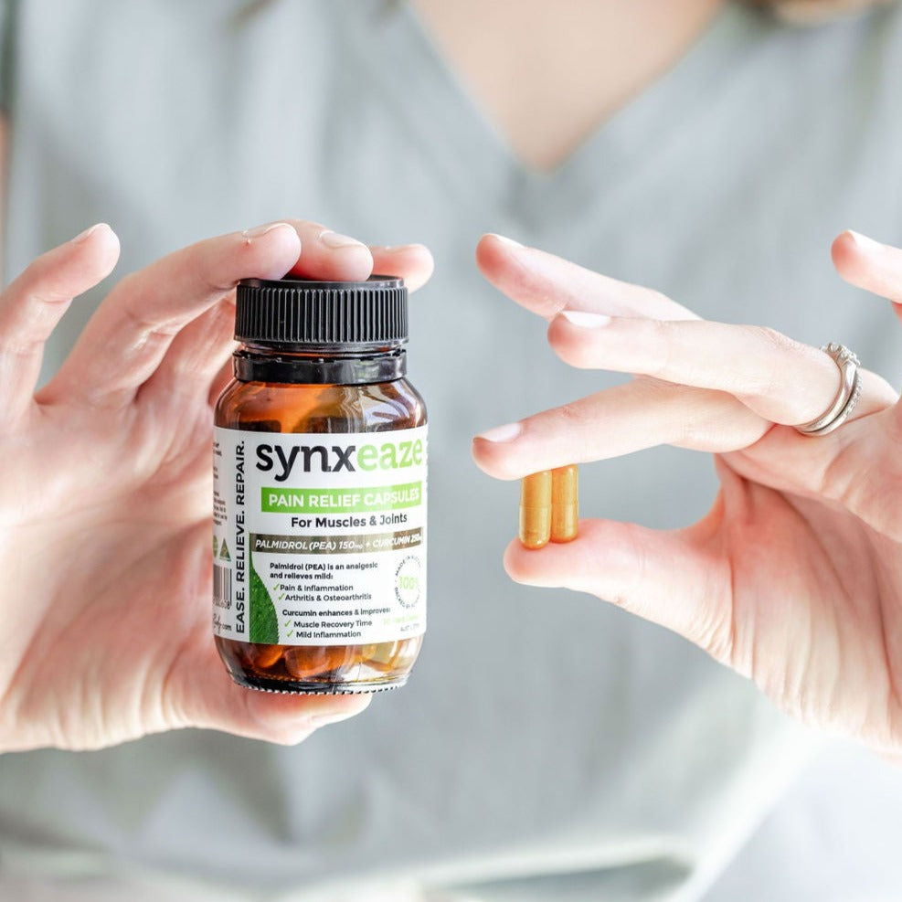 lady's hand holding synxeaze pain relief capsules, relieve mild pain, improves muscle, recovery time, ease inflammation, contains PEA, made in australia