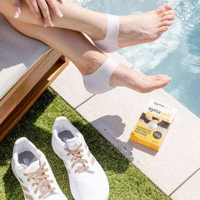 lady sitting by side of pool wearing synxgeli heel socks which are a barrier for bony deformities at the back of the heel and relieve dry cracked heels