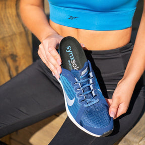 lady inserting synxsole one stop insole into sneaker, align the body, support feet, support lower limbs, protect joints