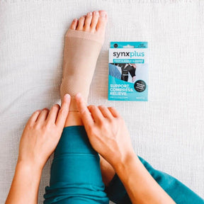 a man placing a synxplus foot and ankle compression sleeve on his foot to assist relieve pain, swelling, inflammation