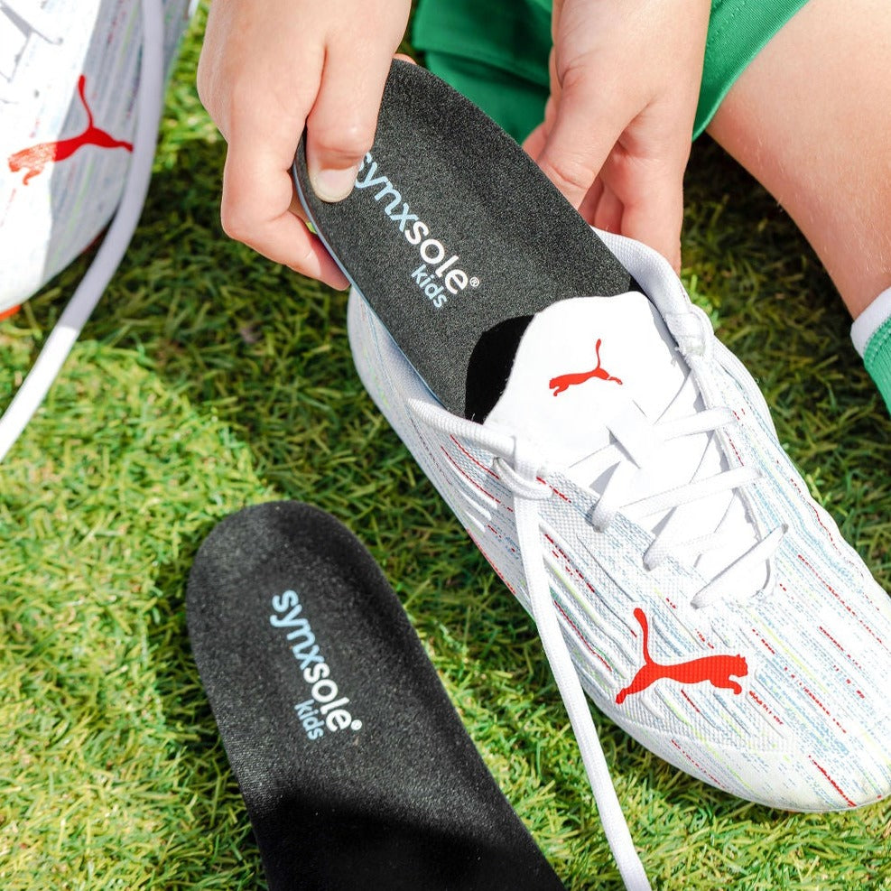 young boy inserting synxsole kids insole into puma sneakers, severs disease, growing pains