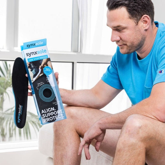 man holding up synxsole packet and insoles, align the body, support feet, support lower limbs, protect joints
