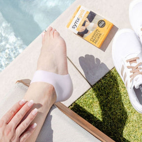 lady sitting by side of pool wearing synxgeli heel socks which are a barrier for bony deformities at the back of the heel and relieve dry cracked heels