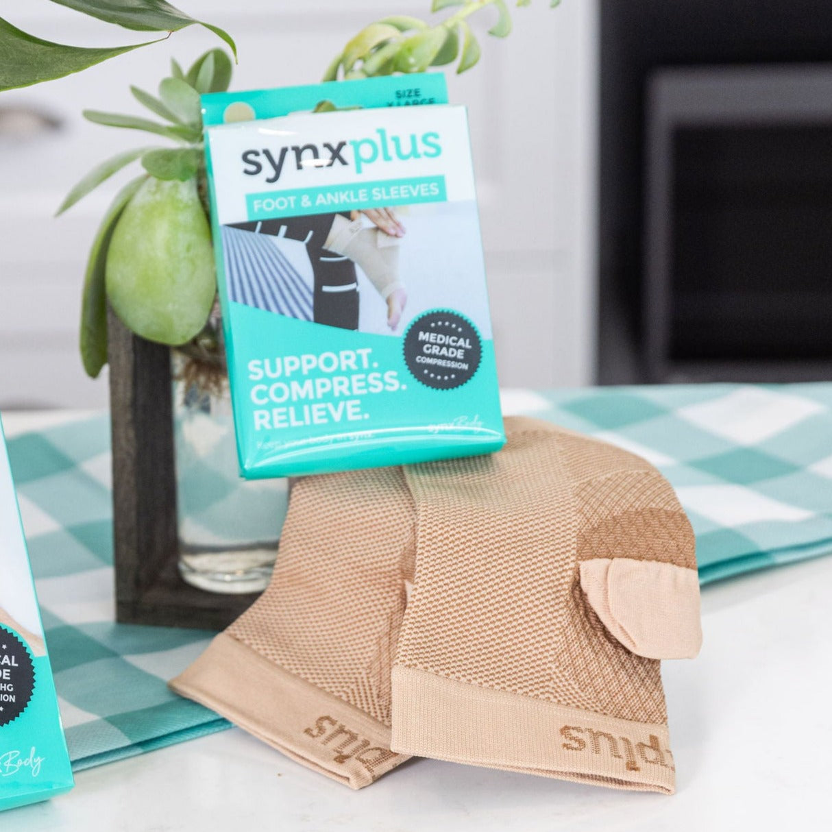 packet of synxplus foot and ankle compression sleeve on his foot to assist relieve pain, swelling, inflammation laying on a bench