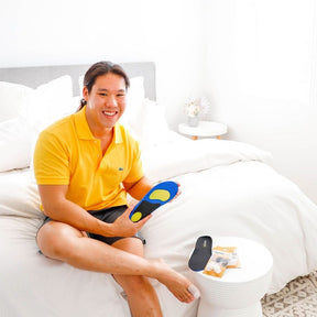 man sitting on bed holding up synxgeli power insole  to cushion, protect and relieve the soft tissue and joints