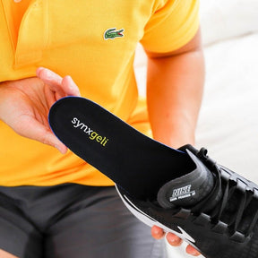 man wearing yellow tshirt inserting synxgeli power insole into sneaker to cushion, protect and relieve the soft tissue and joints