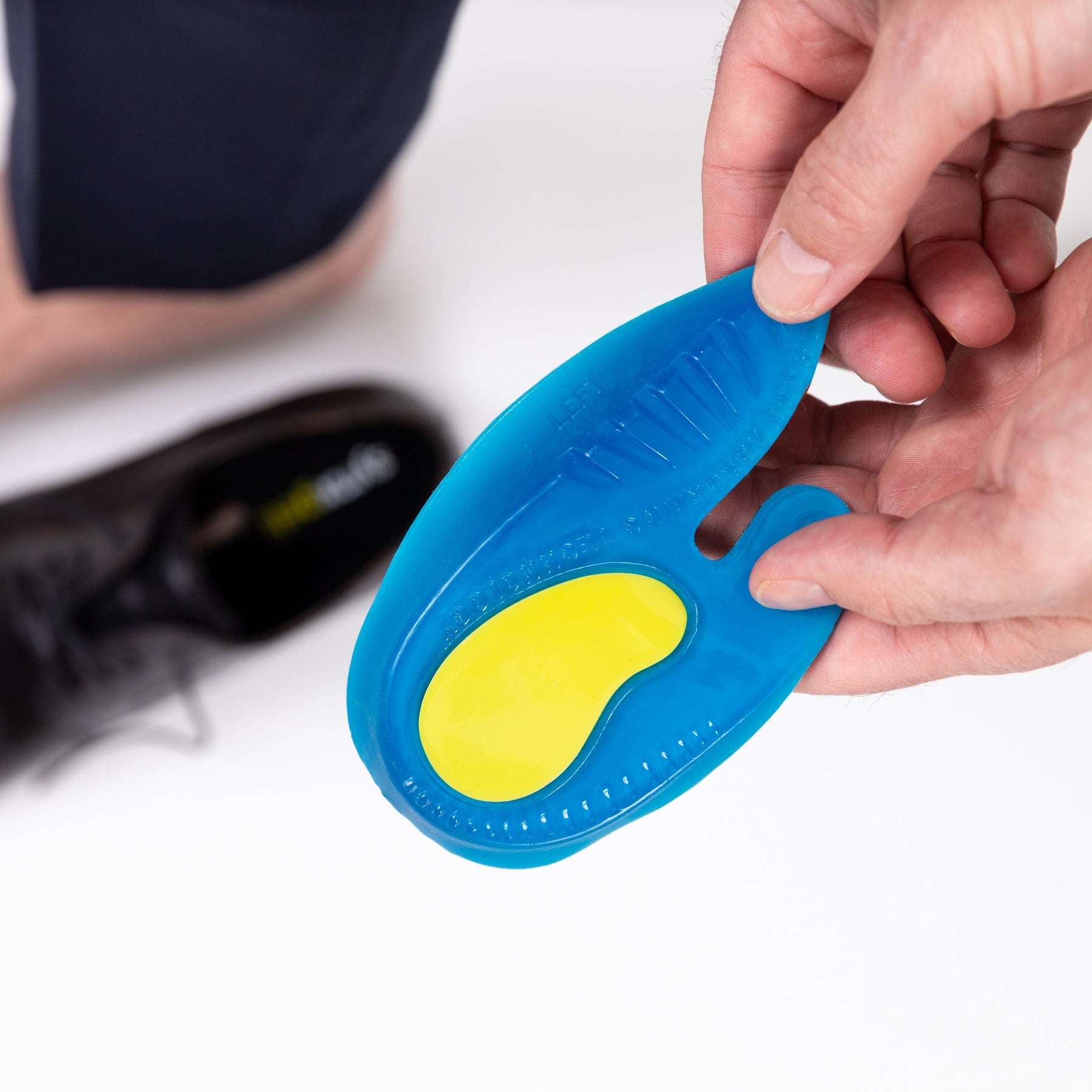 man holding up a synxgeli heel cushion designed to cushion, protect and relieve the heel and Achilles